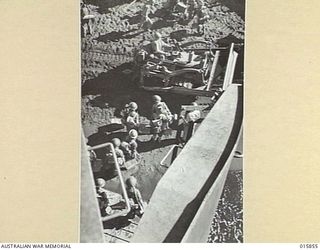 1943-09-28. LAE SALAMAUA ISOLATED. THROUGH A V FOR VICTORY MADE BY A DOOR IN THE BOW OF A BEACH LANDING CRAFT AND THE HULL, AUSTRALIANS STREAM ON TO THE BEACH AFTER THE LANDING NORTH WEST OF LAE