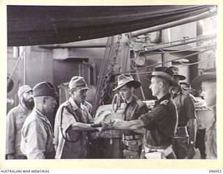 BOUGAINVILLE, 1945-09-18. A JAPANESE LIEUTENANT COLONEL, ACCOMPANYING MAJOR GENERAL KIJIMA, HANDING HIS SWORD TO CAPTAIN W. DAVIES ABOARD THE DEBORAH IN NUMA NUMA HARBOUR. THE SWORD WAS ACCEPTED ON ..