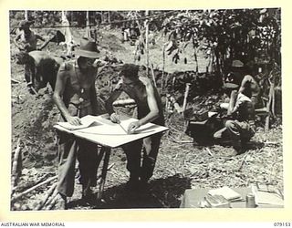 TSIMBA AREA, BOUGAINVILLE ISLAND. 1945-02-17. VX69250 WARRANT OFFICER II, J.E. SANDFORD, GROUP OFFICER, 4TH FIELD REGIMENT (1) AND VX73688 BOMBARDIER N.R. GROWSE (2) WORKING ON AN ARTILLERY ..