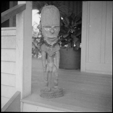 Full figure carving with an elongated head, on a verandah, Awar [?], Sepik River, New Guinea, 1935, 2 / Sarah Chinnery