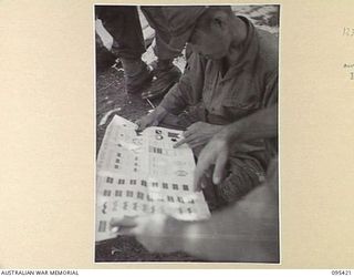 KIARIVU, NEW GUINEA, 1945-08-14. WARRANT OFFICER 2 T. HEALEY, THE AUSTRALIAN NEW GUINEA ADMINISTRATIVE UNIT REPRESENTATIVE QUESTIONS A JAPANESE PRISONER IN THE 2/7 INFANTRY BATTALION AREA. HE ..