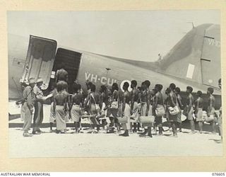 MADANG, NEW GUINEA. 1944-10-18. V310843 PRIVATE W.E. DAY (1) AND VX10345 CORPORAL T.G MIDDLETON (2), 8TH MOVEMENT CONTROL GROUP, LOADING NATIVES ABOARD A DOUGLAS C47 AIRCRAFT FOR THEIR TRIP TO LAE