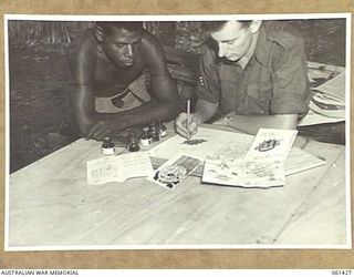 DUMPU, NEW GUINEA. 1943-12-06. QX26891 LANCE SERGEANT D. J. GRIMLEY OF HEADQUARTERS, 7TH AUSTRALIAN DIVISION, CLOSELY WATCHED BY A NATIVE, DESIGNING GAILY COLOURED CHRISTMAS CARDS TO SEND HOME TO ..