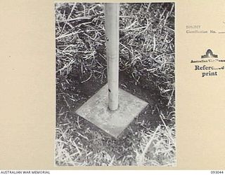 LAE AREA, NEW GUINEA, 1945-06-15. THE STEEL BASE PLATE OF AN IMPROVISED AERIAL MAST AT 19 L OF C SIGNALS. THIS IS AN ORDINARY 15 INCH X 15 INCH STAY PLATE RESTING ON THE SURFACE OF THE GROUND WITH ..