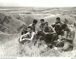 FINISTERRE RANGES, NEW GUINEA. 1943-12-20. MEMBERS OF C COMPANY, 2/31ST AUSTRALIAN INFANTRY BATTALION, 25TH AUSTRALIAN INFANTRY BRIGADE ENJOYING LUNCH ON THE TOP OF A RIDGE OVERLOOKING THE RAMU ..