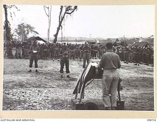 DALLMAN HARBOUR, NEW GUINEA. 1945-11-11. MEMBERS OF 2/5 INFANTRY BATTALION BOW THEIR HEADS IN REMEMBRANCE AS CHAPLAIN W.B. HOWDEN READS THE NAMES OF FALLEN COMRADES DURING A MEMORIAL SERVICE HELD ..