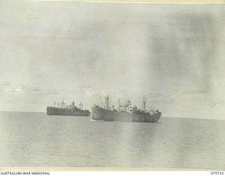 AT SEA. 1944-09/08. SHIPS OF THE CONVOY GUARDED BY THE RAN CORVETTE, GEELONG, PARTLY OBSCURED BY A HEAVY PALL OF SMOKE FROM THEIR ESCORTING VESSEL AS THEY PROCEED ALONG THE COAST OF NEW GUINEA