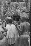 Mortuary ceremony, Omarakana: women present fiber skirt valuables to widow who sits in doorway of small mourning house