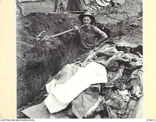 LAE, NEW GUINEA. 1944-07-01. WHILE DIGGING THIS TRENCH, AN EXTENSION TO THE QUARTERMASTER STORE DRAINAGE SYSTEM, QX30427 SERGEANT S. BROWNE OF HEADQUARTERS, NEW GUINEA FORCE (1) FOUND THREE CASES ..