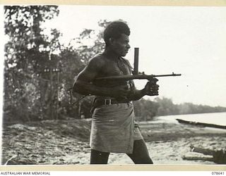 BOUGAINVILLE ISLAND. 1945-01-25. NGN47 LANCE-CORPORAL GINDUA "A" COMPANY, 1ST NEW GUINEA INFANTRY BATTALION FIRING AN OWEN GUN DURING A UNIT REFRESHER COURSE