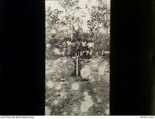 Bitapaka, New Britain. 1915-01-05. Group portrait of RAN members of the Australian Naval and Military Expeditionary Force (AN&MEF) standing behind a pipe mine which they have been digging out on ..