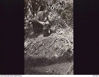 LAE, NEW GUINEA. 1943-09-19. QX10801 DRIVER J. M. HOY, HEADQUARTERS, 9TH AUSTRALIAN DIVISION, WASHES HIS CLOTHES BESIDE A MOUNTAIN STREAM
