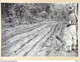 BOUGAINVILLE, 1945-07-31. AN INFANTRYMAN OF 29 INFANTRY BRIGADE LOOKING ALONG THE BUIN ROAD WEST OF THE OGORATA RIVER. DUE TO HEAVY RAINS THE ROAD HAS NOW BECOME A QUAGMIRE AND THE ONLY MEANS OF ..