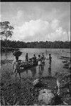 Canoes: woman carries large basket on head to canoe being loaded