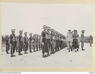 JACQUINOT BAY, NEW BRITAIN, 1945-07-01. HIS ROYAL HIGHNESS, THE DUKE OF GLOUCESTER, GOVERNOR-GENERAL OF AUSTRALIA (1), TAKING THE SALUTE FROM HEADQUARTERS 4 INFANTRY BRIGADE TROOPS DURING THE MARCH ..