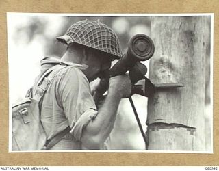 DONADABU AREA, NEW GUINEA. 1943-11-30. QX37757 PRIVATE K. H. WAGNER OF THE 2/10TH AUSTRALIAN INFANTRY BATTALION USING A BARR AND STROUD RANGEFINDER DURING THE COMBINED EXERCISES WITH THE 2/4TH ..