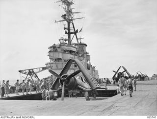 AT SEA OFF RABAUL, NEW BRITAIN. 1945-09-06. CORSAIR AIRCRAFT COMING UP IN THE LIFT TO THE FLIGHT DECK OF AIRCRAFT CARRIER HMS GLORY. THE CORSAIRS PROVIDED AIR COVER DURING THE SIGNING OF THE ..