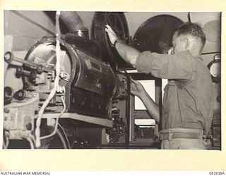 LAE AREA, NEW GUINEA. 1944-11-12. SERGEANT G. SIMPSON, AUSTRALIAN ARMY AMENITIES SERVICE ATTACHED HQ FIRST ARMY, FEEDS THE SPECIAL RELEASE COPY OF THE 1944 MELBOURNE CUP INTO A PROJECTOR