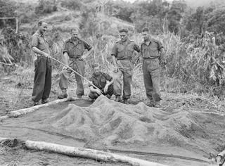 KARAWOP, NEW GUINEA. 1945-05-05. LIEUTENANT C.E. BEGG, INTELLIGENCE OFFICER, 2/1 INFANTRY BATTALION (1), DISCUSSING OPERATIONS USING A SAND MODEL OF THE KARAWOP AREA AND INLAND HILLS. IDENTIFIED ..