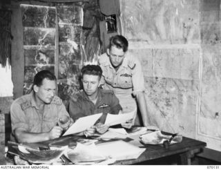 RAMU VALLEY, NEW GUINEA. 1944-01-02. VX20171 LIEUTENANT J.R. FETHERSON-HAUGH (1) STUDYING AERIAL PHOTOGRAPHS WITH 408844 FLYING OFFICER S.R. HOOPER (2); AND 415987 FLYING OFFICER L.G. ELLERS (3) ..