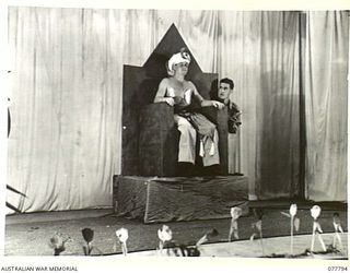 LAE BASE AREA, NEW GUINEA. 1944-12-27. A SCENE FROM "ALI CAZAZIS" DURING THE CHRISTMAS CONCERT STAGED IN THE AUDITORIUM OF THE 22ND WORKS COMPANY. SEEN IS:- V55375 PRIVATE B. MORGAN (1)