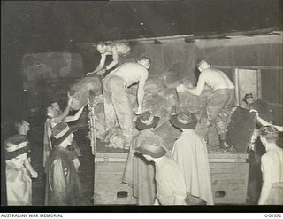 KIRIWINA, TROBRIAND ISLANDS, PAPUA. C. 1943-12. IN TORRENTIAL RAIN RAAF AIRMEN UNLOADING A TRUCK LOADED WITH CHRISTMAS MAIL FOR THE POST OFFICE