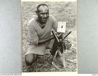 1943-06-15. NEW GUINEA. A PAPUAN INFANTRY UNIT. A NATIVE SOLDIER WHO RECEIVED THE MILITARY MEDAL FOR WORKING BEHIND JAPANESE LINES AND OBTAINING VALUABLE INFORMATION, PHOTOGRAPHED ON THE RANGE WITH ..