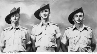 Group portrait of three members of 2/22 Battalion. Left to right: probably VX46697 Anthony Richard John Fox, of Macarthur, Victoria; VX26758 Private (Pte) George William Lanham, of Albury, NSW; and ..