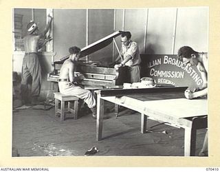 PORT MORESBY, PAPUA, NEW GUINEA, 1944-02-14. CARPENTERS AND A PIANO TUNER AT WORK IN STUDIO 2 IN PREPARATION FOR THE OPENING OF THE AUSTRALIAN BROADCASTING COMMISSION RADIO STATION 9PA. THE OFFICER ..