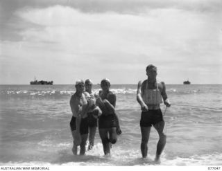 TOROKINA, BOUGAINVILLE, 1944-11-19. THE SURF LIFE SAVING TEAM OF THE 2/8TH CAVALRY COMMANDO SQUADRON BRINGING THEIR "PATIENT" ASHORE DURING A DEMONSTRATION AT THE SURF CARNIVAL ARRANGED BY ..