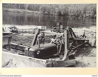 JACQUINOT BAY, NEW BRITAIN, 1945-08-08. A HEAVY CRANE BEING TOWED BY TRACTOR TO THE LANDING SHIP, TANK (LST) DURING MOVEMENT OF 41 LANDING CRAFT COMPANY TO BORNEO. THE TRACTOR AND THE CRANE ARE ..