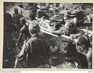 BOUGAINVILLE. 1945-04-26. STRETCHER BEARERS CARRYING TPR C. PARKER, 2/4 ARMOURED REGIMENT (1), SHOT THROUGH THE LEG DURING 24 INFANTRY BATTALION'S ADVANCE ALONG BUIN ROAD SOUTH OF SINDOU RIVER. ..