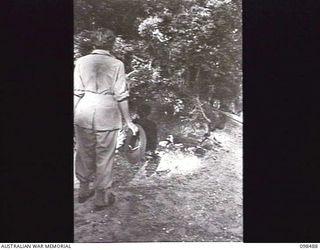 KOIL ISLAND, NEW GUINEA, 1945-10-31. SISTER N. MCDONAGH, 104TH CASUALTY CLEARING STATION, INSPECTING A NATIVE GRAVE ON KOIL ISLAND. THE NATIVES OF THE ISLAND WHEN BURYING ONE OF THE TRIBE PLACE A ..