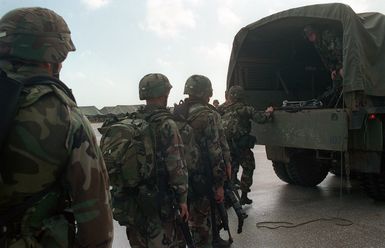 US Army (USA) Soldiers assigned to A/Company, 1ST Battalion, 17th Infantry Division carrying weapons and field packs load onto a transport truck, in preparation for Non-combatant Evacuation Operations (NOE) at Orote Point, Guam during Exercise TANDEM THRUST '99