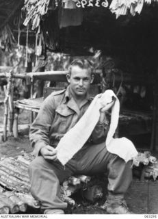 FAITA, NEW GUINEA. 1944-01-07. NX12782 TROOPER L. W. ISENHOOD OF MEREWETHER, NSW, AND OF THE 2/2ND COMMANDO SQUADRON DISPLAYING A BELT OF A THOUSAND STITCHES - A LUCKY CHARM BELT WORN BY A JAPANESE ..