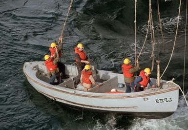 Crew members lower a Mark 10 motor whaleboat into the water from the amphibious assault ship USS GUAM (LPH 9) during Exercise SOLID SHIELD '87