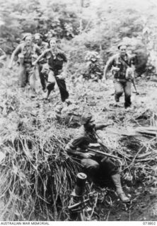 Karkar Island, New Guinea. 1944-06-03. Troops of the 37/52nd Infantry Battalion move towards a pit containing a 3 inch mortar. Left to right: V197621 Private J. King; VX104809 Corporal R. J. ..