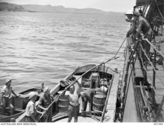 BOERA POINT, NEW GUINEA. 1943-10-01. TRANSFERRING THE BEACH END OF THE NEW SUBMARINE CABLE FROM THE SS MERNOO TO A BARGE. THIS SECTION OF THE CABLE IS SPECIALLY PREPARED TO PROTECT IT FROM THE SUN ..