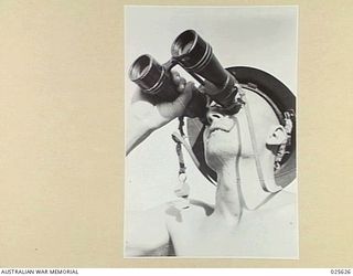PORT MORESBY, PAPUA. 1942-07. LOOKING FOR JAPANESE ZEROS AND BOMBERS, THE KEEN EYES OF THE SPOTTER OF AN AUSTRALIAN ANTI-AIRCRAFT CREW SEARCHES THE NEW GUINEA SKY