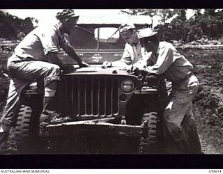 DREGER HARBOUR, NEW GUINEA. 1943-11-02. OFFICERS OF THE 808TH UNITED STATES ENGINEER AVIATION BATTALION, WITH A JEEP FOR A TABLE, CHECKING OVER PLANS FOR THE NEW AIRSTRIP. LEFT TO RIGHT: CAPTAIN ..