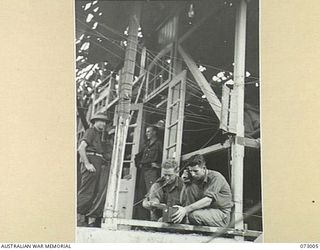 MADANG, NEW GUINEA. 1944-04-25. NX118459 CORPORAL G. FORD, AND NX57156 SERGEANT A. PARKER, MEMBERS OF 8TH INFANTRY BRIGADE SIGNALS. TESTING NEWLY INSTALLED TELEPHONE LINES AT THE OLD HOTEL MADANG