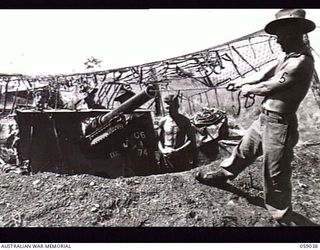 RAMU VALLEY, NEW GUINEA. 1943-10-23. TROOPS OF THE 54TH BATTERY, 2/4TH AUSTRALIAN FIELD REGIMENT PULLING THROUGH WHILE CLEANING A 25-POUNDER GUN. NOTE THE CAMOUFLAGE NET. LEFT TO RIGHT: VX14409 ..