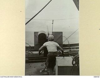 AT SEA, BETWEEN FINSCHHAFEN, NEW GUINEA AND BIAK. 1945-04-04. PRIVATE R.H. GANTT, A US ARMY GUNNER ABOARD THE VAN HEUTSZ FIRES HIS .50 INCH HEAVY ANTI-AIRCRAFT MACHINE GUN AT A PARACHUTE TARGET ..