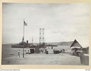 RABAUL, NEW BRITAIN. 1945-10-03. THE ROYAL AUSTRALIAN NAVY DEPOT AT RABAUL ON THE SHORES OF SIMPSON HARBOUR. HMAS DUBBO AND A JAPANESE TUG ON LEFT AND HMAS SWAN ON RIGHT