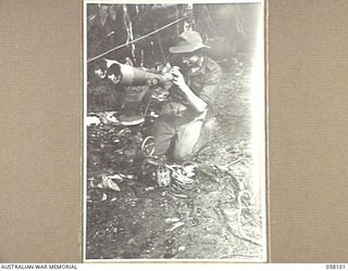 FINSCHHAFEN, NEW GUINEA, 1943-10-02. NX39663 PRIVATE J.F. SMITH, 9TH AUSTRALIAN DIVISION, EXAMINES A HUGE PAIR OF JAPANESE BINOCULARS WHICH WERE CAPTURED BY AN AIF BATTALION DURING THE CAMPAIGN