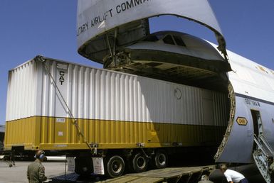 Members of the 22nd Military Airlift Squadron guide a trailer-load of generator hardware into a C-5 Galaxy aircraft headed for Pago Pago, American Samoa