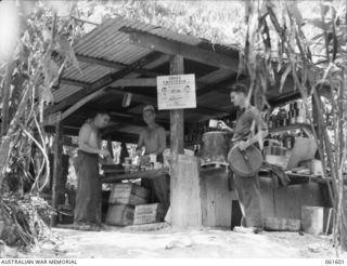 FINSCHHAFEN AREA, NEW GUINEA. 1943-11-24. JUNGLE COOKHOUSE OF THE 2/3RD AUSTRALIAN FIELD COMPANY, ROYAL AUSTRALIAN ENGINEERS. SHOWN ARE: SX494 CORPORAL R. A. COLES OF ADELAIDE, SA, (1); SX513 ..