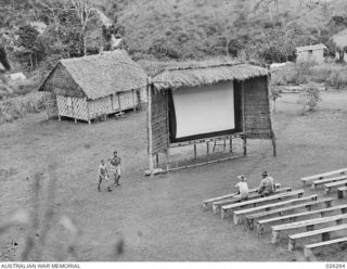 PAPUA. 1942-08-18. EARLY ARRIVALS FOR THE FILM SHOW. AUSTRALIAN TROOPS OF THE 21ST AUSTRALIAN INFANTRY BRIGADE TAKING UP THEIR POSITIONS FOR THE OUTDOOR PICTURE SHOW. THE FRAMEWORK FOR THE CINEMA ..