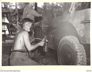 PALMALMAL PLANTATION, JACQUINOT BAY, NEW BRITAIN, 1945-06-06. PRIVATE J. WARD (1) AND PRIVATE G. VEIVERS (2), MEMBERS OF 1 INFANTRY TROOPS WORKSHOP SPRAY PAINT A COMPLETED JEEP. THEY ARE ON THE ..