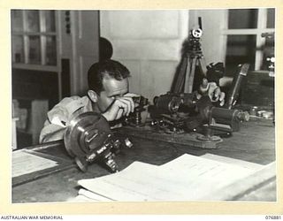 LAE AREA, NEW GUINEA. 1944-11-15. THE NON COMMISSIONED OFFICER- IN- CHARGE OF THE INSTRUMENT WORKSHOPS 2/7TH ADVANCED WORKSHOPS, QX4425 STAFF SERGEANT E. RAWLINGS CALIBRATING A PAIR OF BINOCULARS ..